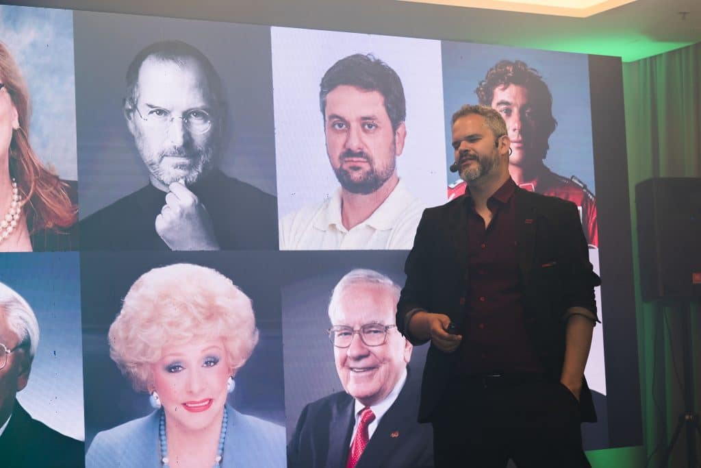 Palestrante da Paul & Jack apresenta conteúdo de liderança diante de telão com referências visuais de grandes nomes.
