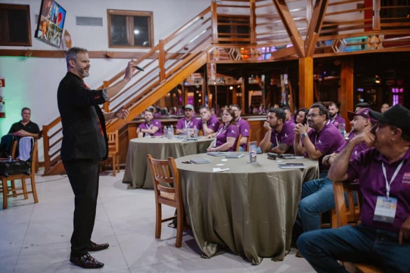 Palestrante realizando apresentação interativa para equipe corporativa durante evento empresarial em ambiente descontraído.