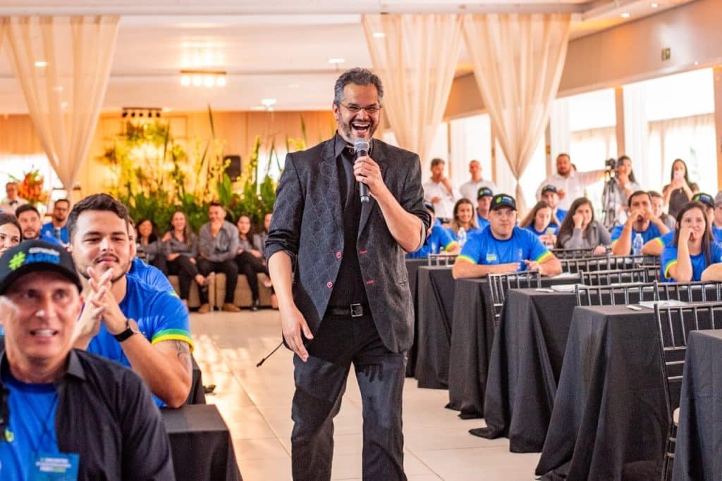 Palestrante conduzindo uma palestra motivacional corporativa com público engajado em evento empresarial.