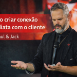 Paul, palestrante de vendas e comunicação, em palco, segurando um microfone e observando as próprias mãos durante uma apresentação. Imagem de capa do artigo “Como criar conexão imediata com o cliente”.