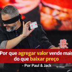 Palestrante realizando demonstração com cartas de baralho, vendado, em palco, usando terno escuro, com faixa vermelha destacando o título sobre valor e preço ao fundo.