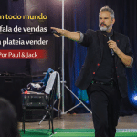 Palestrante em palco apontando para a plateia durante evento corporativo, com o título “Nem todo mundo que fala de vendas faz a plateia vender – Por Paul & Jack”.