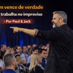 Palestrante de perfil, apontando para a plateia durante apresentação corporativa, com o título “Quem vence de verdade não trabalha no improviso – Por Paul & Jack”.