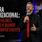 Capa de artigo em formato 16:9 com Paul & Jack em destaque no palco, em cena corporativa de forte presença, sobre fundo escuro e textura grunge. À esquerda, aparece o título “Cultura organizacional: por que valores só existem quando viram comportamento”, com a assinatura “Por Paul & Jack”.